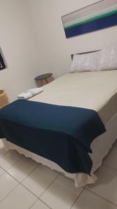 a bed with a blue blanket on it in a room at Ap charmoso in Mossoró +2 photos
