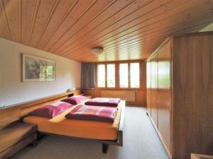 a bedroom with a bed with pink pillows on it at Apartment Appartement Eggmatte by Interhome in Grimmialp