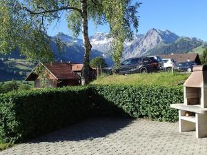 a hedge in front of a house with a tree and mountains at Apartment Frohmatt by Interhome in Adelboden