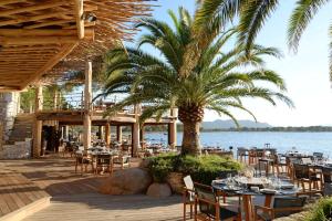 a restaurant with tables and chairs and a palm tree at Hôtel Le Belvédère in Porto-Vecchio