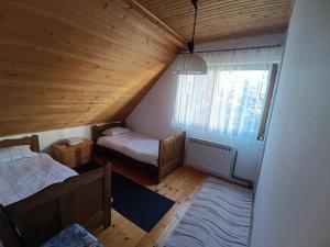 an attic room with two beds and a window at Vikendica SANA Vlašić in Šišava