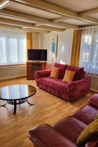 a living room with a red couch and a table at Apartment Chalet Lilo Big view by Interhome in Beatenberg