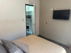 a bedroom with a bed and a flat screen tv on the wall at Aquí es 5 !! in Banfield