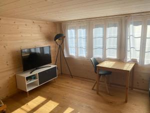 a living room with a television and a table and a desk at Apartment Alpenruh by Interhome in Gadmen