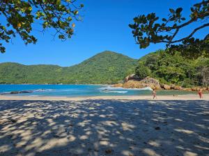two people walking on a beach with mountains in the background at Flats Alto das Pedras in Trindade