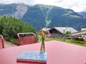 a vase of flowers on a pink table with a mountain at Apartment Aspa EG by Interhome in Bellwald