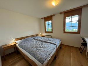 a bedroom with a bed and a desk and two windows at Apartment Aspa EG by Interhome in Bellwald