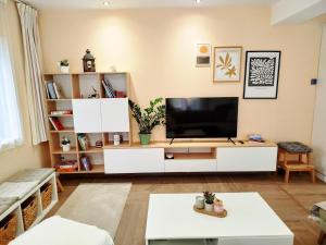 ein Wohnzimmer mit Fernseher und weißem Entertainment-Center in der Unterkunft Oliami in Acharavi