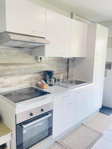 a white kitchen with white cabinets and a stove at Excellence Suites Orient Beach Oceanview King-Size Beach Pool Parking in Cul de Sac