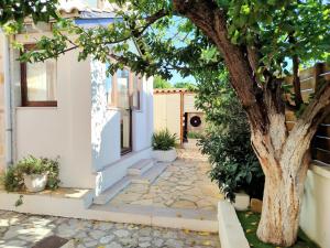 ein Haus mit einem Baum neben einem Gehweg in der Unterkunft Oliami in Acharavi