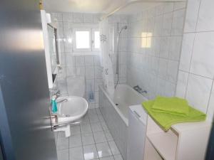 a white bathroom with a sink and a bath tub at Apartment Alter Konsum by Interhome in Bellwald