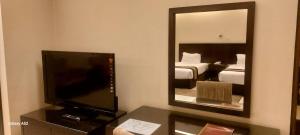 a hotel room with a television and a mirror at The Avenue Hotel & Suites in Chittagong