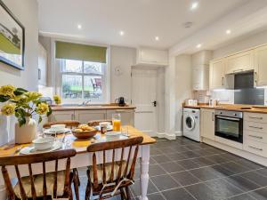 a kitchen with a wooden table and chairs and a kitchen with a stove at 2 Bed in Keswick oc-sz006 in Keswick