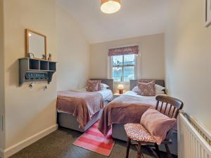 a bedroom with two beds and a chair and a window at 2 Bed in Keswick oc-sz006 in Keswick