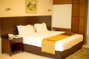 a bedroom with a large bed and a telephone at The Avenue Hotel & Suites in Chittagong +16 photos