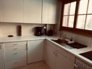 a kitchen with white cabinets and a sink and a window at Apartment Chalet Bacchus - EG by Interhome in Sörenberg