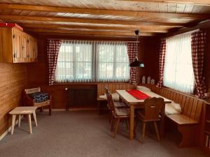 a dining room with a table and chairs and windows at Apartment Chalet Bacchus - EG by Interhome in Sörenberg