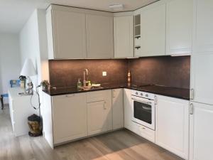 a kitchen with white cabinets and a sink at Apartment Weggis by Interhome in Weggis