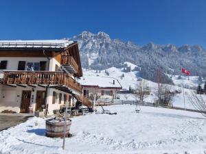 a building with a snow covered yard in front of a mountain at Apartment Sonnehüsli by Interhome in Flühli
