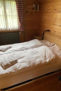 a white bed in a wooden room with a window at Apartment Chalet Bacchus - OG by Interhome in Sörenberg