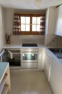a small kitchen with a stove and a sink at Apartment Chalet Bacchus - OG by Interhome in Sörenberg