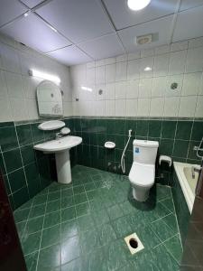 a green tiled bathroom with a toilet and a sink at ALEX Hostel - Bed in a shared room - C504 in Sharjah +22 photos