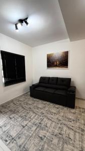 a living room with a black couch and a window at Duplex completo, perto da praia e no centro de Imbé in Imbé