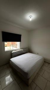 a bedroom with a bed and a window at Duplex completo, perto da praia e no centro de Imbé in Imbé