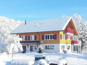 a house with red and yellow doors in the snow at Apartment S'Ottä by Interhome in Sattel