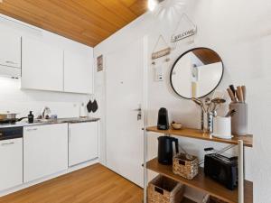 a kitchen with white cabinets and a mirror on the wall at Apartment Lake View Studio by Interhome in Ingenbohl