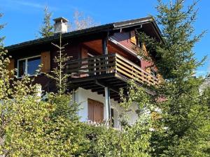 a large wooden house with a balcony in the trees at Apartment Chalet Hörler direkt im Ski- und Wandergebiet by Interhome in Emmetten
