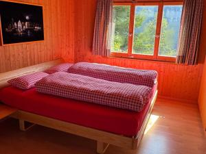 a bed with four pillows in a room with a window at Apartment Chalet Hörler direkt im Ski- und Wandergebiet by Interhome in Emmetten