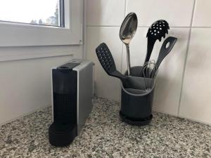 a cup with utensils in it on a counter at Apartment Studio Rubi Weggis by Interhome in Weggis +11 photos