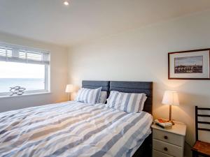 a bedroom with a bed with a striped comforter and a window at 2 Bed in Berwick-upon-tweed oc-82189 in Spittal