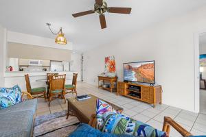a living room with a couch and a flat screen tv at Grand Champions 033 in Wailea