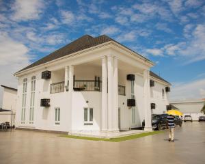 a man standing in front of a white building at Golden Tulip Hotel in Asaba
