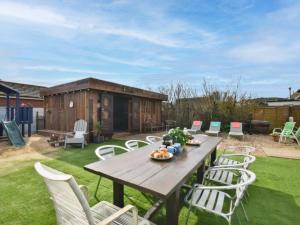 a wooden table and chairs in a yard with a shed at 6 Bed in Rye- oc-89037 in Camber