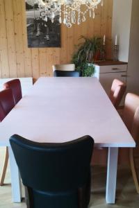 a white dining table with chairs and a chandelier at Apartment Karotte by Interhome in Trub