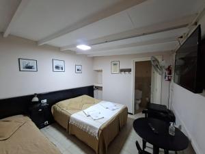 a room with two beds and a table and a tv at Hosteria Marina Bella 3 in Rada Tilly