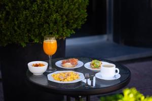 a table with plates of food and a glass of orange juice at DON Boutique Hotel Montevideo in Montevideo
