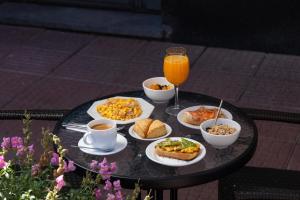 a table with plates of food and a glass of orange juice at DON Boutique Hotel Montevideo in Montevideo