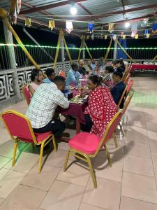 a group of people sitting at a table in a restaurant at Hôtel Restaurant Le Papillon in Goungouamoué