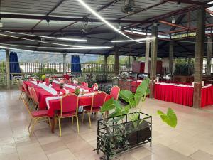 a long table with red tables and chairs in a pavilion at Hôtel Restaurant Le Papillon in Goungouamoué