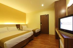 a hotel room with a bed and a flat screen tv at Seasons View Hotel in Kuantan
