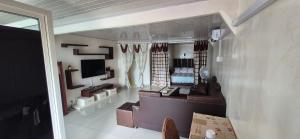 a living room with a couch and a television at Hôtel Restaurant Le Papillon in Goungouamoué
