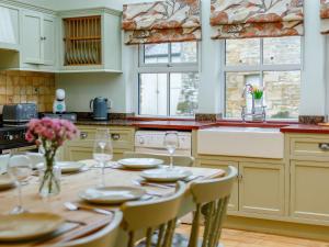 a kitchen with a wooden table with chairs and a tableasteryasteryasteryasteryastery at 4 Bed in Hexham oc-90521 in Bardon Mill