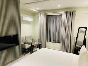 a hotel room with a bed and a chair and a television at Legacy Dreams in Islamabad +18 photos