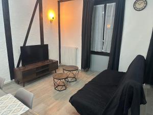 a living room with a flat screen tv and a couch at Duplex au cœur de la Bastide in Villefranche-de-Rouergue