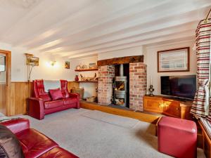 a living room with a brick fireplace and red chairs at 3 Bed in Keswick oc-94346 in Threlkeld