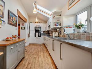a kitchen with white cabinets and a wooden floor at 3 Bed in Keswick oc-94346 in Threlkeld